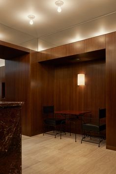 an empty meeting room with wooden walls and marble desks in the center, along with two black chairs