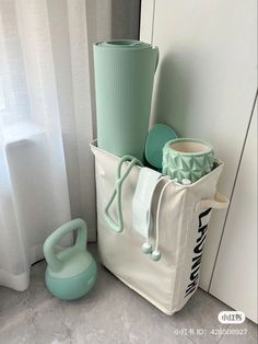 a white tote bag sitting on the floor next to a stack of green items