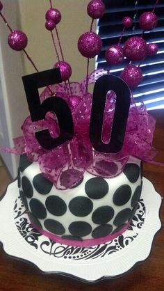 a 50th birthday cake with pink and black decorations