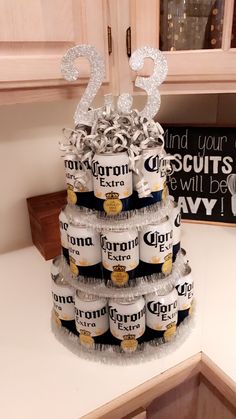 a tiered cake made out of cans with silver numbers on top and white frosting