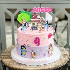 a pink cake with cartoon characters on it sitting on top of a wooden table next to a chair