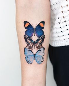 a woman's arm with two blue butterflies on the left side of her arm