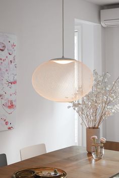 a wooden table topped with a vase filled with white flowers next to a light fixture