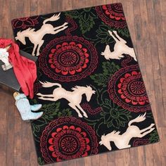 an area rug with horses and flowers on it, next to a pair of shoes