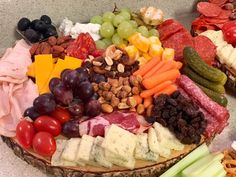 an assortment of cheeses, meats and vegetables on a platter