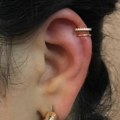 a close up of a person's ear with a gold nose ring and diamond bar