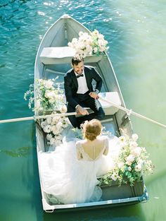 a bride and groom in a row boat on the water