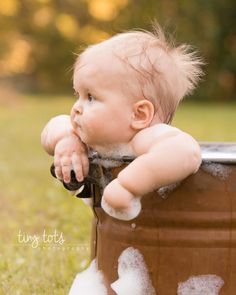 a baby is sitting in a bucket outside