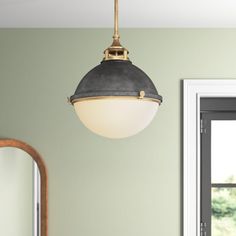 a light fixture hanging from the ceiling over a sink in a room with green walls