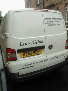 a white van parked on the side of a road next to a brick building with writing on it