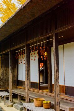 an old building with wooden benches and lanterns hanging from it's roof, in front of trees