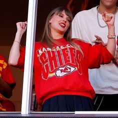 two women and a man are standing in the stands with their hands up to their chests