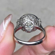 a close up of a person's hand holding a ring with a diamond in it