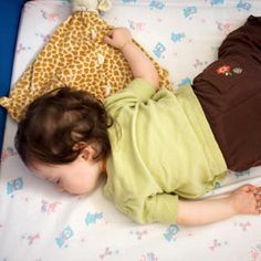 a small child laying on top of a bed next to a stuffed giraffe