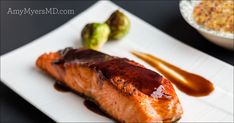 a piece of salmon on a plate with sauce and brussel sprouts