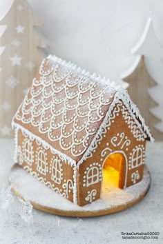 a gingerbread house with icing on it and a lit candle in the center