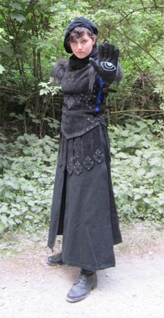 a woman dressed in black is posing for the camera with her gloved hand up