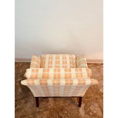 an orange and white checkered couch sitting on top of a wooden floor next to a wall