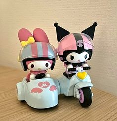 two hello kitty figurines sitting on top of a motor scooter together