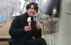 a man sitting down eating an ice cream cone