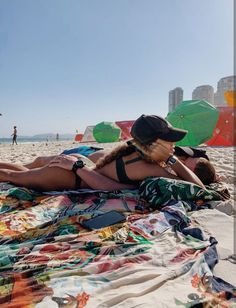 a woman laying on top of a beach covered in blankets