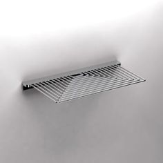 a metal grate hanging from the side of a white wall in an empty room