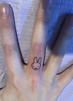 a person's hand with a small rabbit tattoo on the middle of their finger