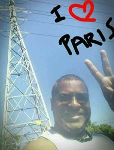 a man with his hand up in front of an electric tower that says i love paris