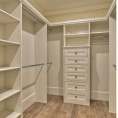 an empty walk in closet with lots of shelves and drawers on the wall, along with wooden flooring