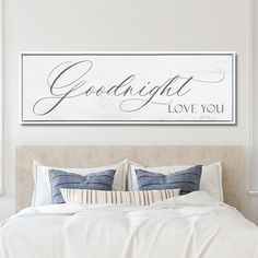 a bedroom with a bed, pillows and a framed sign above it that says goodnight love you