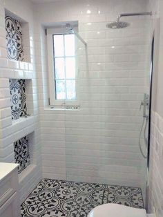 a white bathroom with black and white tile on the floor, shower stall and toilet