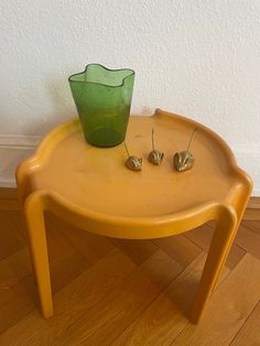 a green vase sitting on top of a yellow table