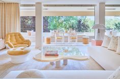 a living room filled with white furniture and lots of windows