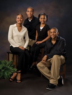 an image of a family posing for a photo in front of a dark background with plants