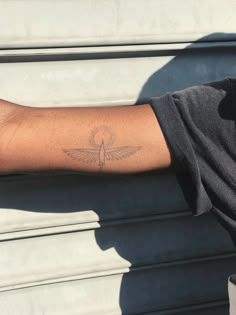 a person's arm with a small bird tattoo on the left side of their arm