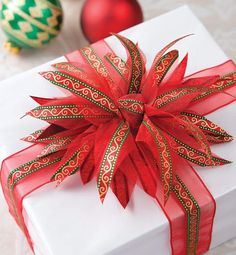 a white gift box with red ribbon and ornaments around it