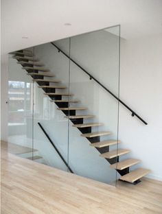 there is a glass stair case next to the wooden floor in this room with white walls