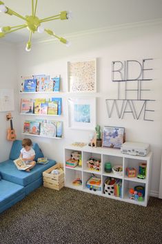 a child sitting on a blue couch in front of a wall with bookshelves