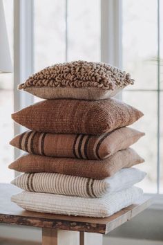 a stack of pillows sitting on top of a wooden table