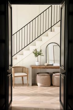 an entryway with a table, stools and mirror on the wall next to stairs