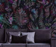 a couch with pillows on it in front of a wallpapered background that has plants and flowers