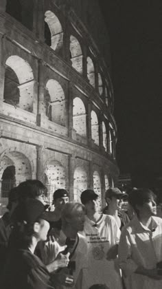 black and white photograph of people standing in front of the colossion at night