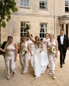 a group of bridesmaids and groomsmid walking in front of a building