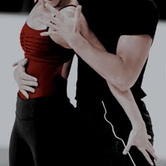 a man and woman dance together in black and red outfits with their arms around each other