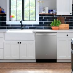 a dishwasher is in the middle of a kitchen with white cabinets and black counter tops