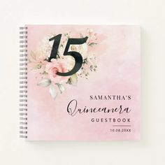 a pink spiral notebook with the number five on it and flowers in front of it