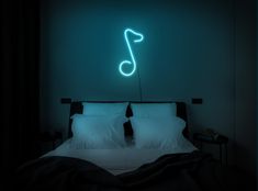 a bed with two pillows and a neon sign above it