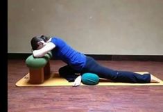 a woman is doing yoga on a mat with her arms behind her head and legs crossed