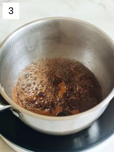 a pan filled with brown liquid on top of a stove