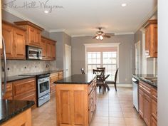 a large kitchen with wooden cabinets and black counter tops, along with a dining room table